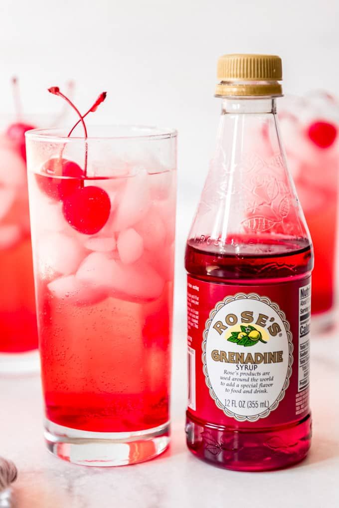 two glasses filled with ice and cherries next to a bottle of boojura