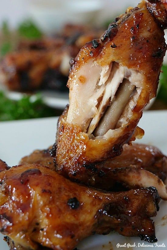 some chicken wings on a white plate with greens