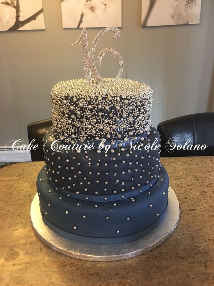 a large blue cake with silver decorations on it's sides and the number sixteen on top