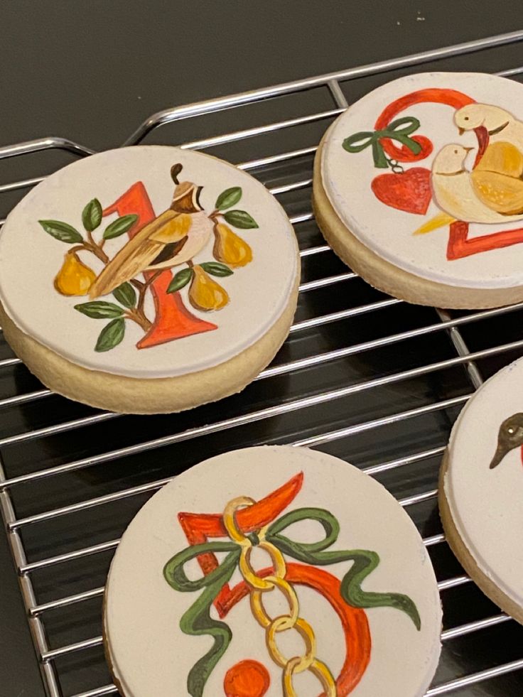 four decorated cookies sitting on top of a cooling rack