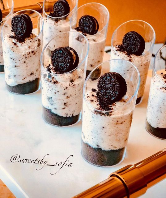 oreo cookies and cream desserts in glasses on a white table with gold pen