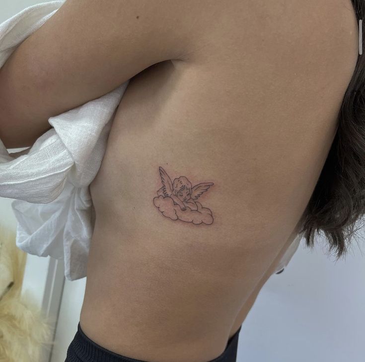 a small tattoo on the back of a woman's left side ribcage