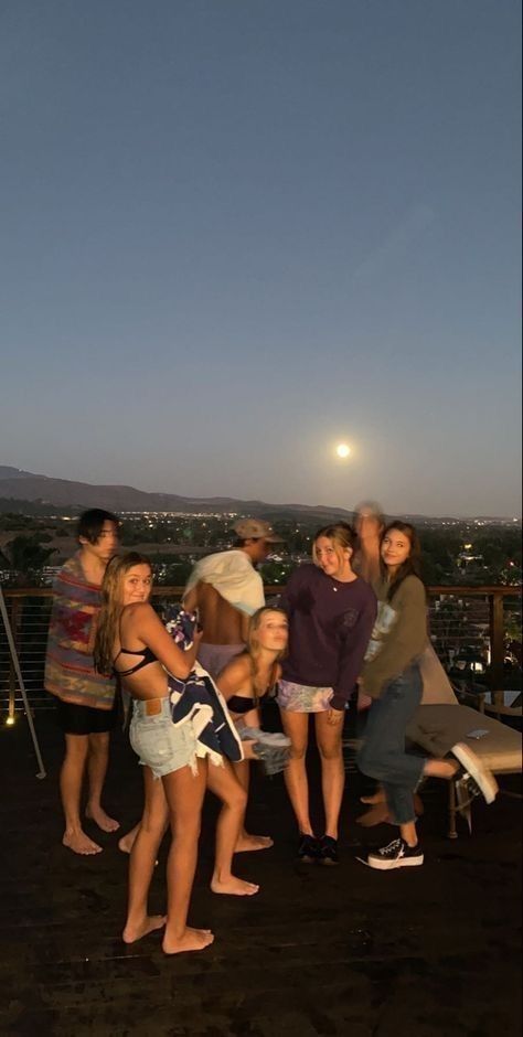 a group of people standing on top of a roof next to each other at night