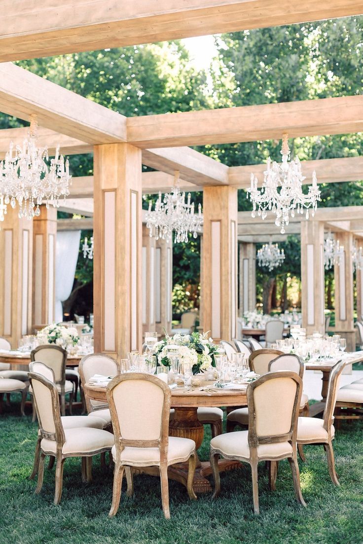 an instagramted photo of a table and chairs with chandeliers hanging from the ceiling