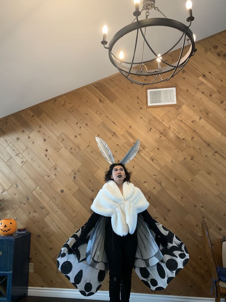 a woman dressed in costume standing next to a chandelier with lights on it