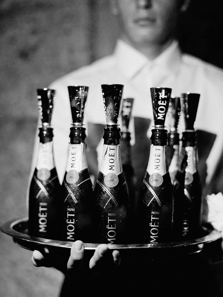 a man holding a tray with bottles of alcohol