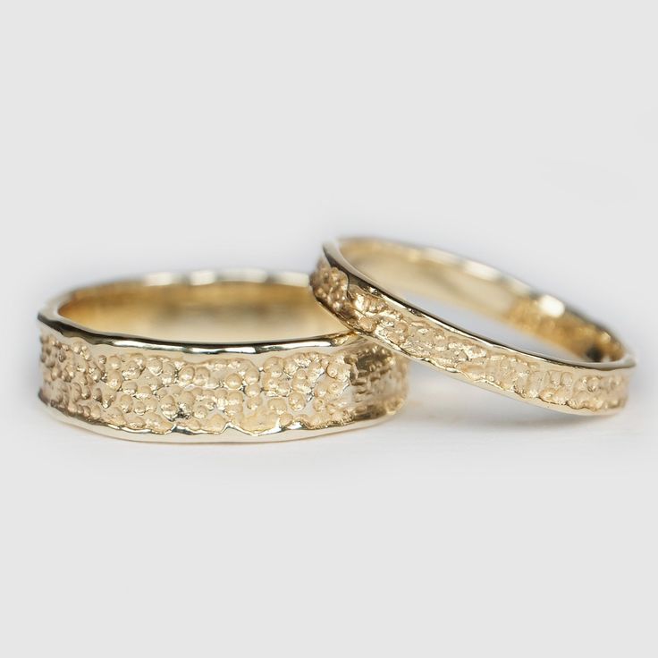 two gold wedding bands with small flowers on the inside and outside, set against a white background