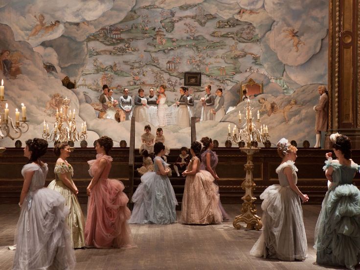 a group of women standing in front of a wall with chandeliers on it