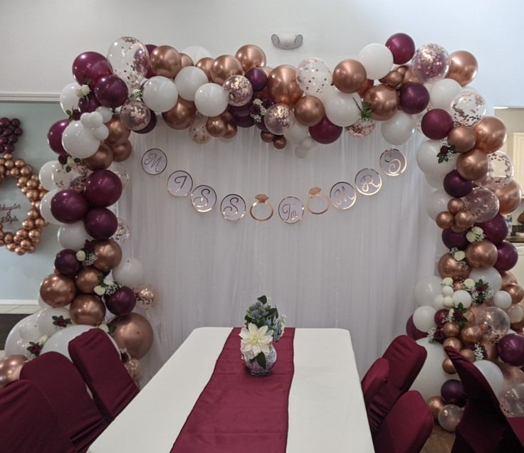 the table is set up for a party with balloons and flowers on it, along with other decorations