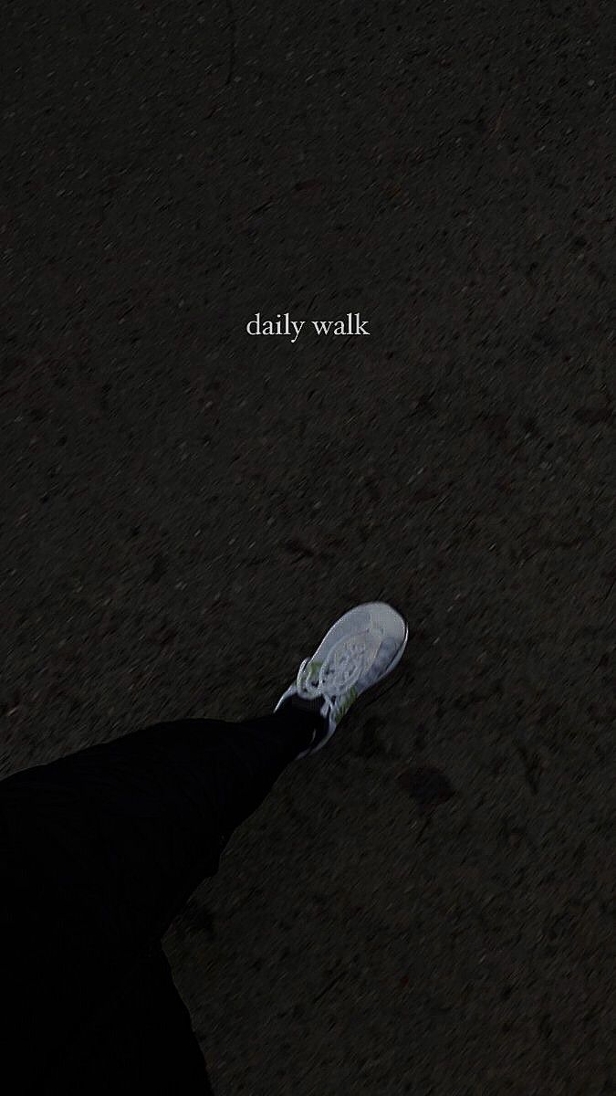 a person standing in the dark with their foot on a tennis shoe that says, daily walk