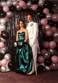 a man and woman standing in front of balloons