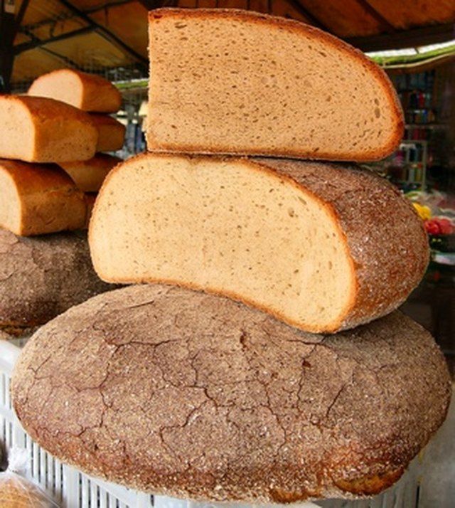 several loafs of bread stacked on top of each other in front of some muffins