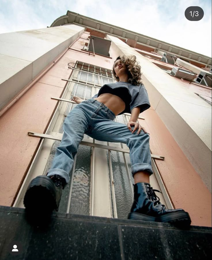 a man sitting on the side of a tall building with his legs crossed and feet in the air