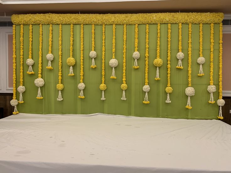 a bed with yellow and white decorations hanging from it's headboard in front of a green wall