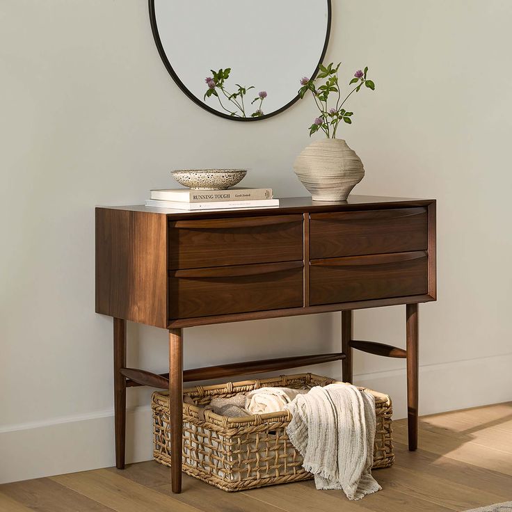 a wooden dresser with two baskets under it and a mirror on the wall behind it