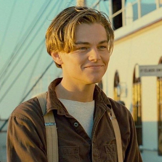 a young man is standing in front of a building and looking at the camera with a smile on his face