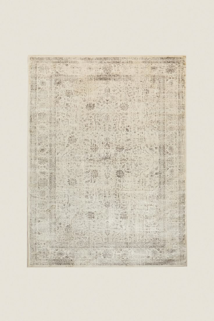 an antique rug with white and grey colors on the bottom, in front of a beige background