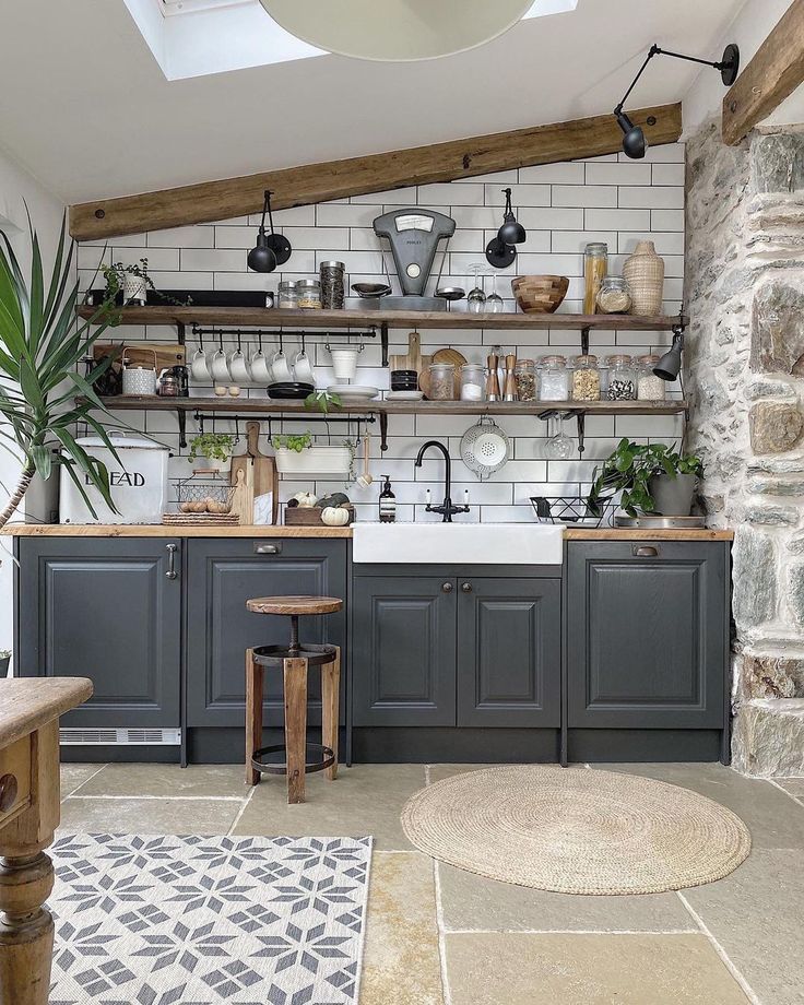 a kitchen with gray cabinets and white brick walls, potted plants on the shelves