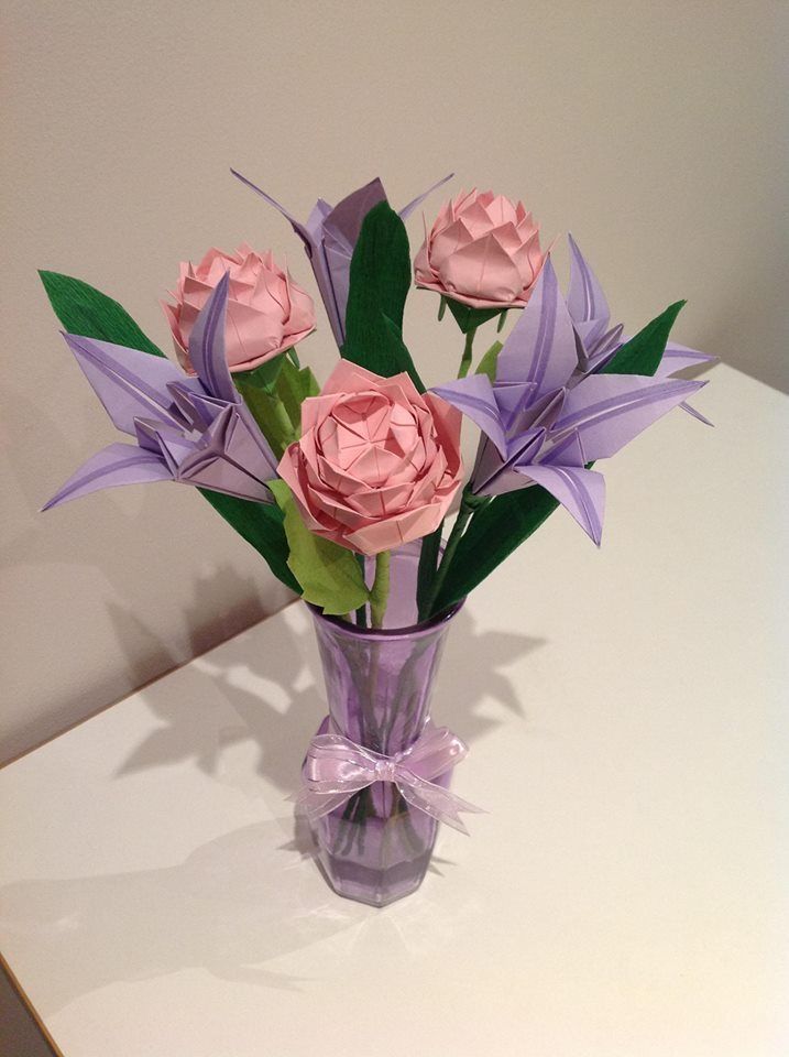 a purple vase filled with pink flowers on top of a white table next to a wall