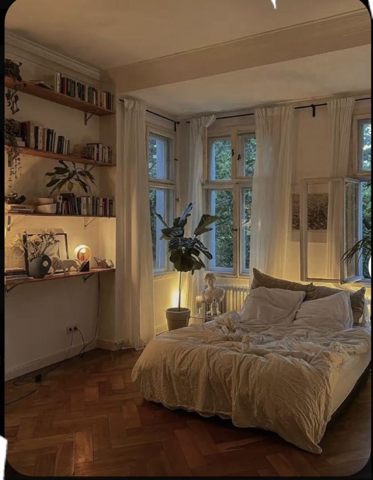 a bed in a room with lots of windows and bookshelves on the wall