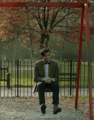 a man sitting on a swing holding a baby