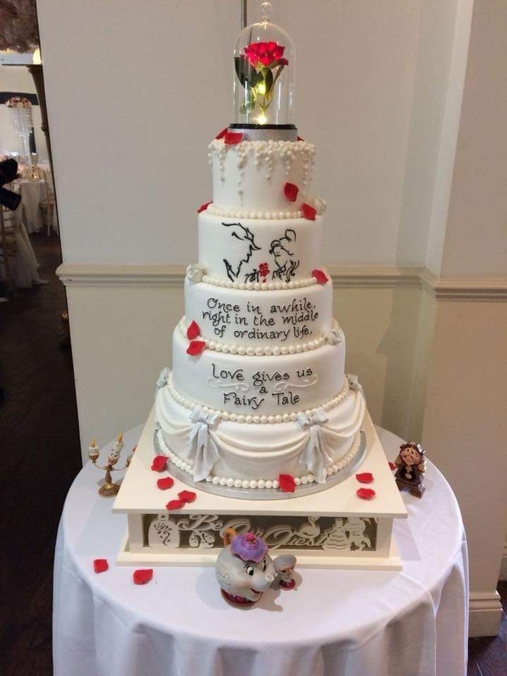 a three tiered wedding cake sitting on top of a white tablecloth covered table