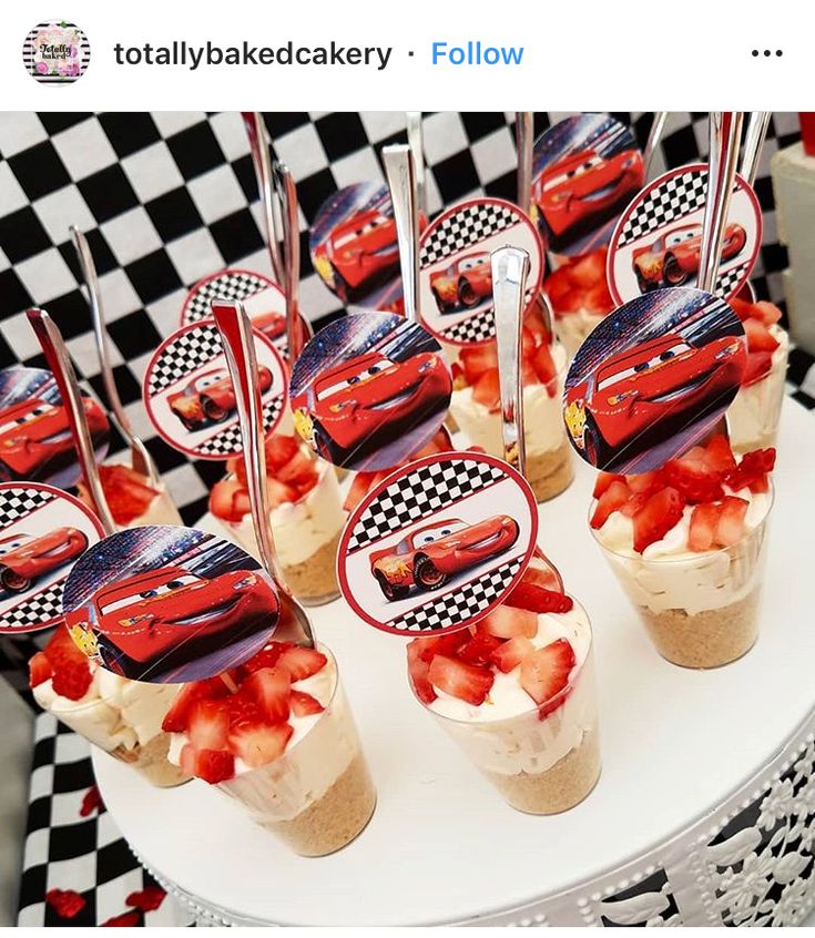 cars desserts are displayed on a table with checkered cloth and red strawberries