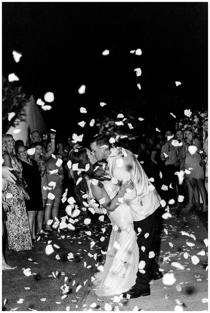 a bride and groom kiss as confetti falls around them