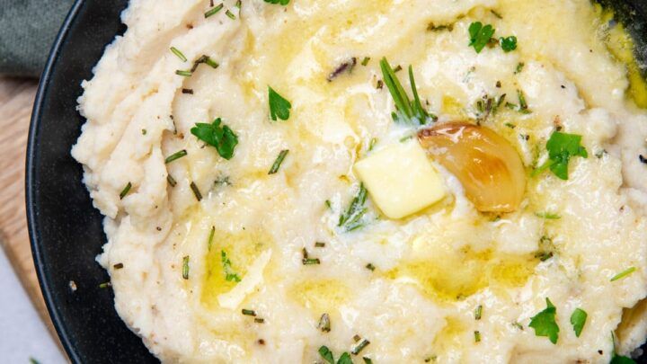 mashed potatoes with garlic and parsley in a black bowl on a wooden table