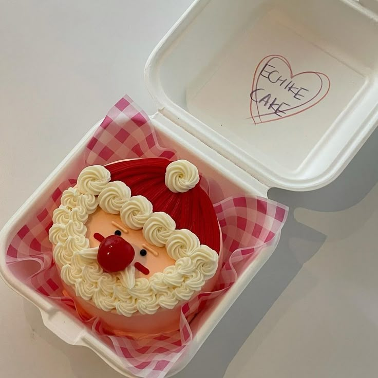 a plastic container with a cake in the shape of a santa claus face on it