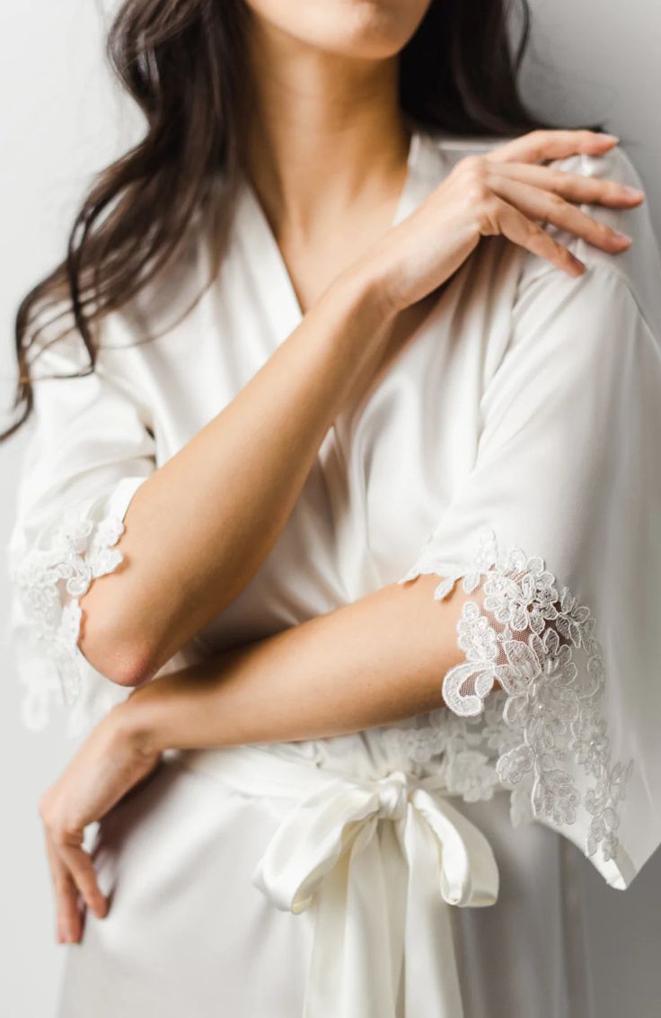 a woman wearing a white robe and holding her hands on her chest