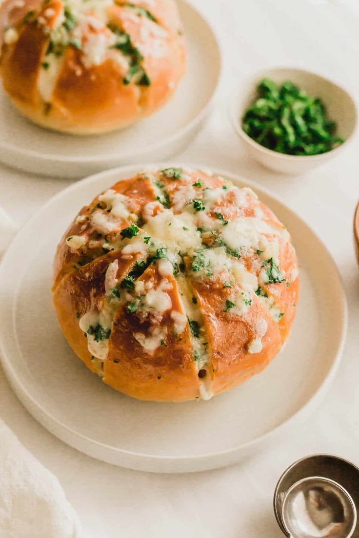 two white plates topped with bread covered in cheese and spinach sprinkles