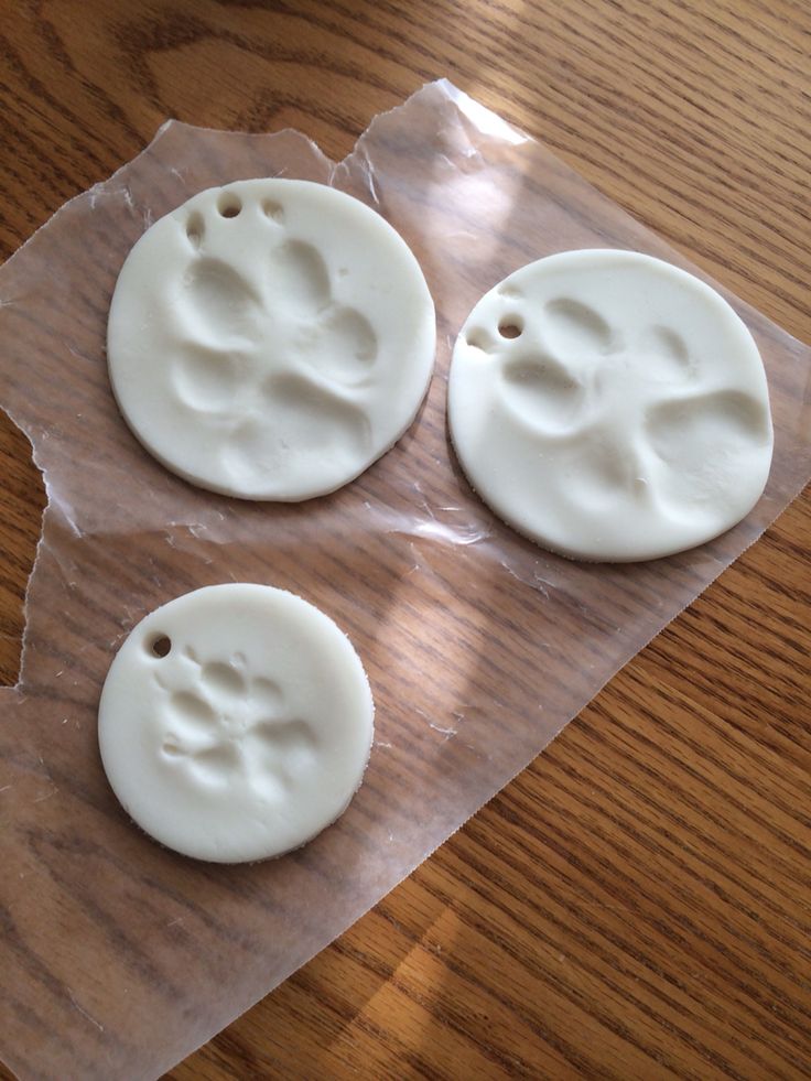 three white plastic buttons sitting on top of a piece of waxed paper next to a wooden table