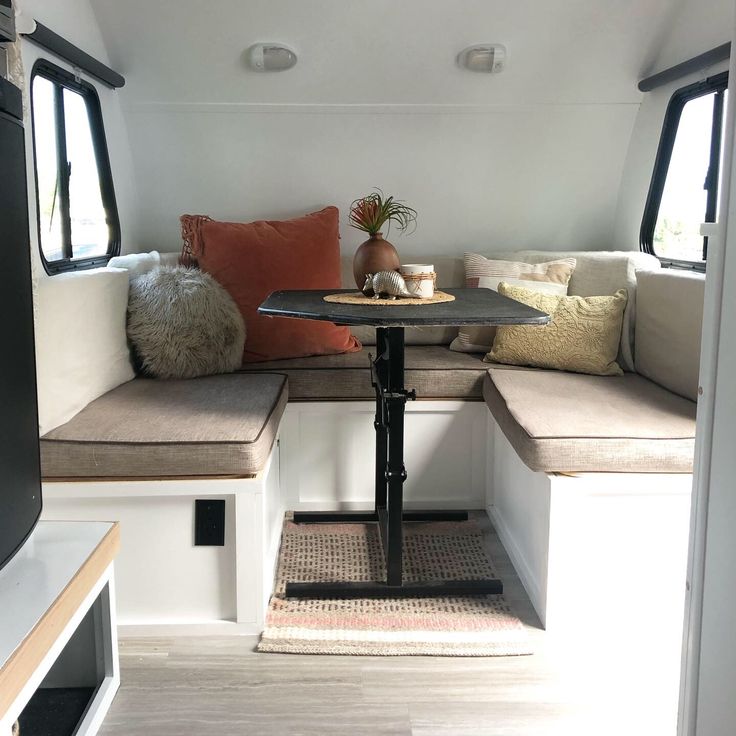 the inside of a camper with couches, tables and pillows on top of it