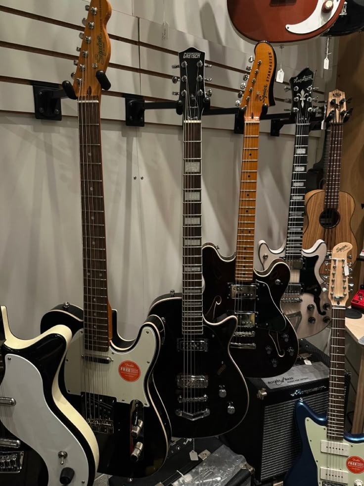 several guitars are lined up on display in a music store, with one being black and the other is white