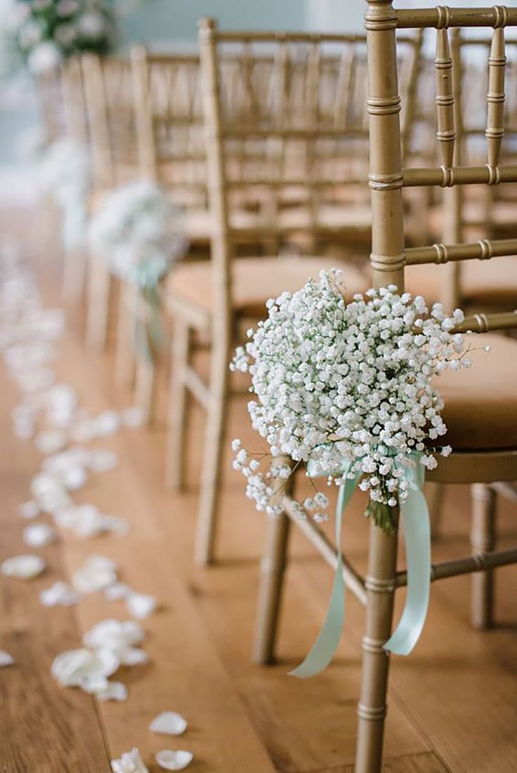 wedding aisle decorated with baby's breath flowers and petals on the floor in front of rows of chairs