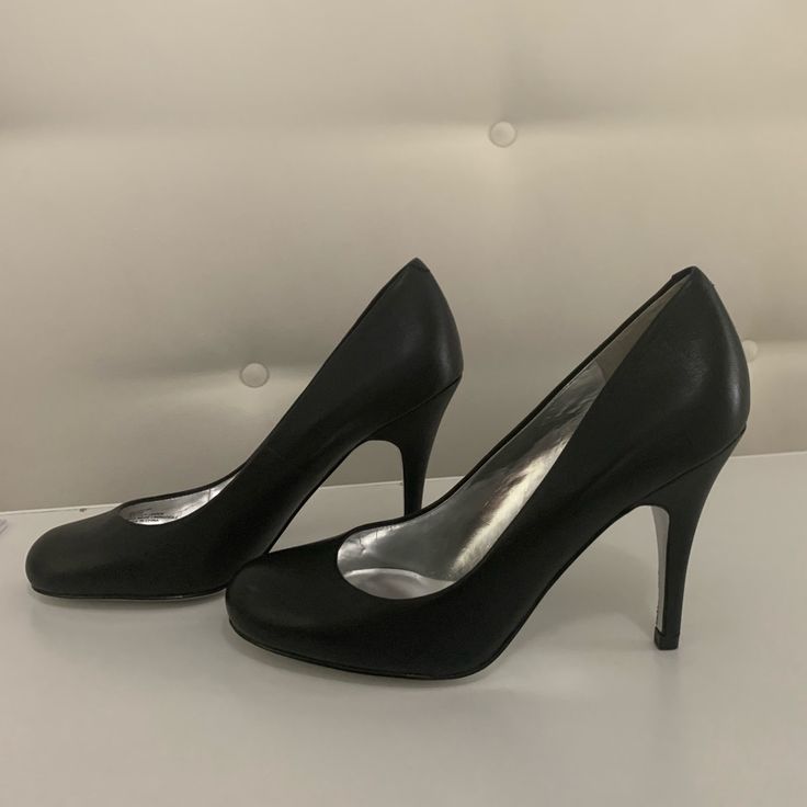 a pair of black high heeled shoes sitting on top of a white table