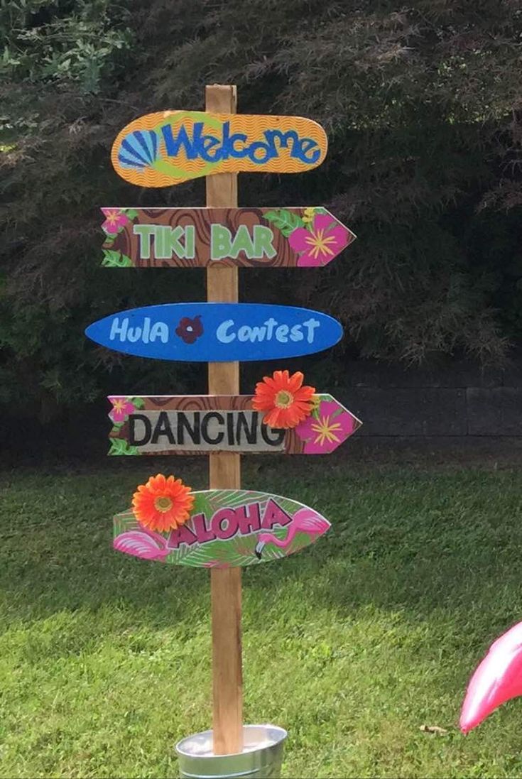 a wooden sign with many different signs on it's side in front of some grass