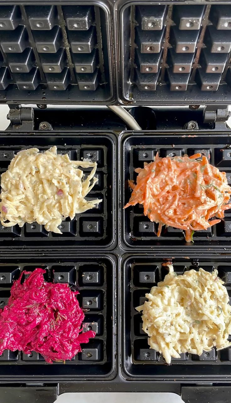 four waffles with different colored toppings on them sitting in plastic trays