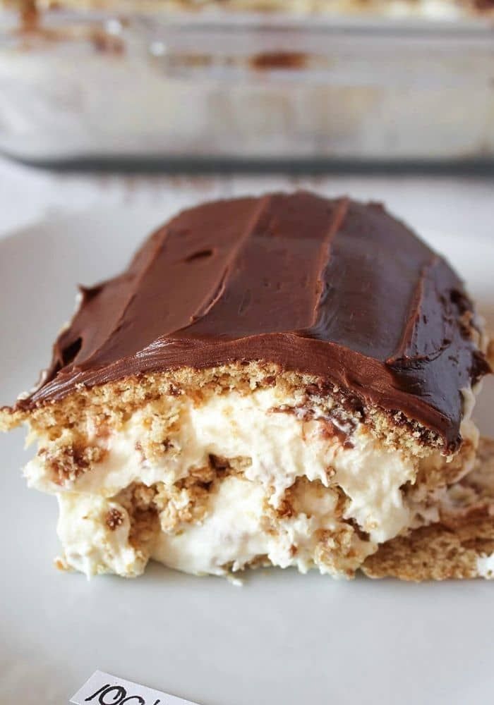 a piece of cake with chocolate frosting and nuts on it sitting on a plate