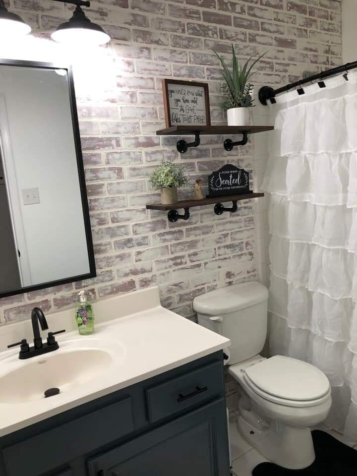 a white toilet sitting next to a bathroom sink under a mirror on top of a wooden shelf