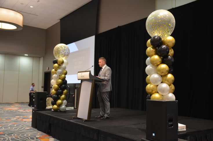 a man standing at a podium in front of balloons