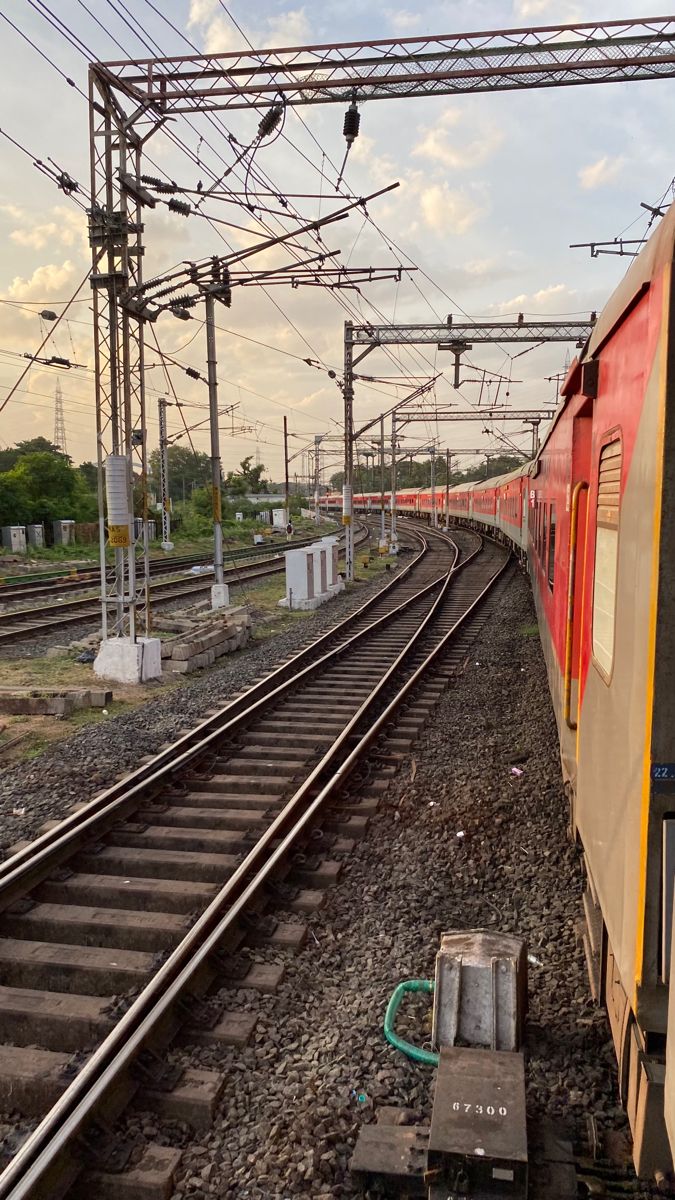 an orange and yellow train traveling down train tracks next to power lines on a cloudy day