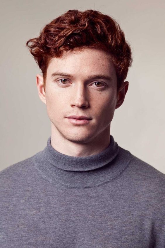 a young man with red hair wearing a turtle neck sweater and looking at the camera