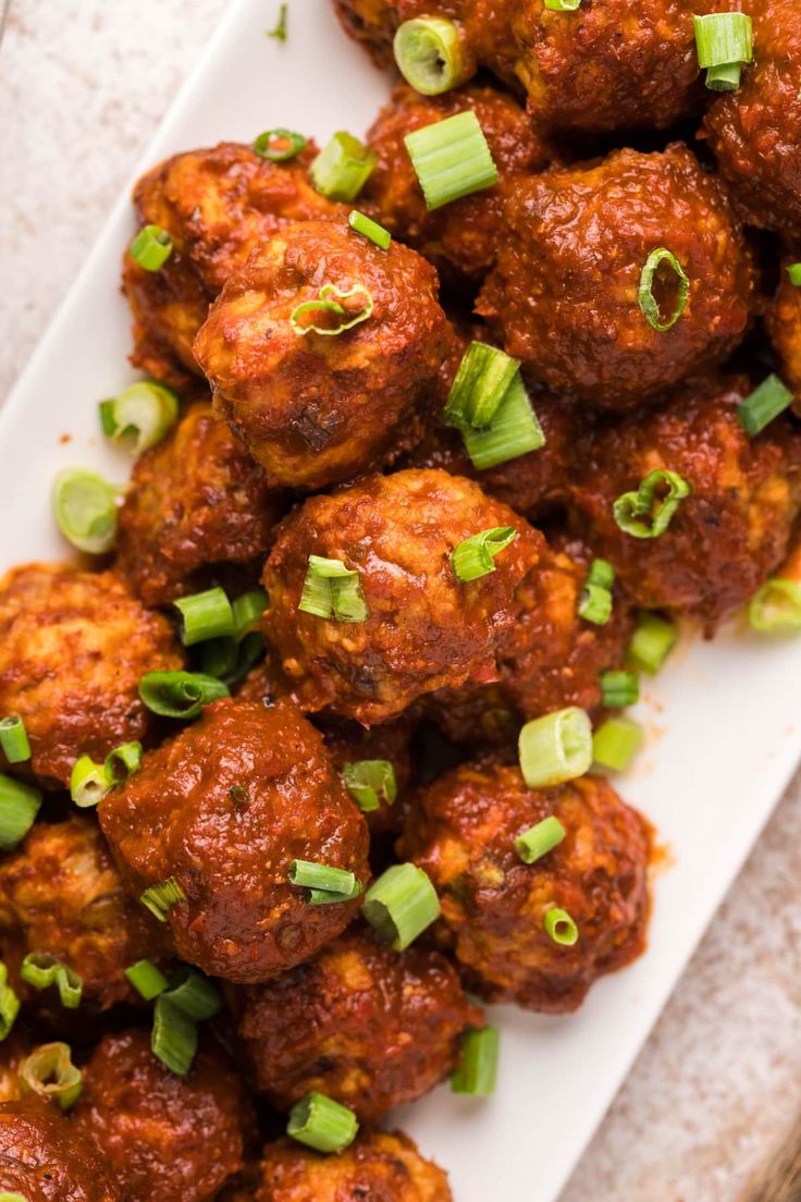 meatballs with green onions on a white plate