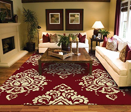 a living room filled with furniture and a red rug on top of a hard wood floor