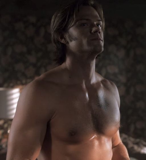 a man without a shirt standing in a room