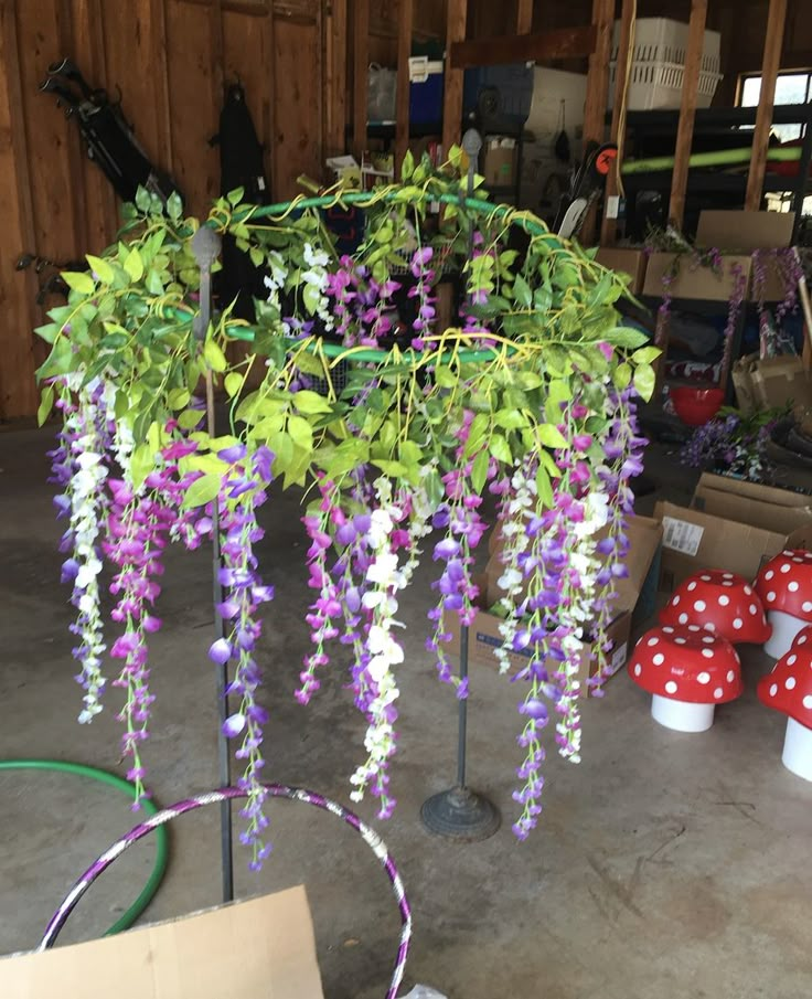 purple and white flowers are hanging from a pole in a garage with other items nearby