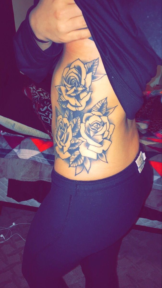 a woman's stomach with roses tattooed on the side and her lower back tattoo