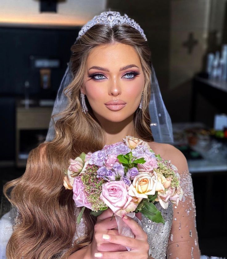 a woman in a bridal gown holding a bouquet of flowers and looking at the camera